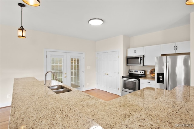 kitchen with french doors, white cabinets, sink, hanging light fixtures, and stainless steel appliances