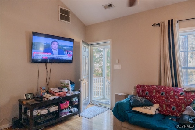 doorway with a wealth of natural light, light hardwood / wood-style flooring, and lofted ceiling