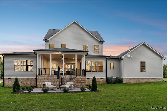 back house at dusk with a lawn, a patio area, and ceiling fan