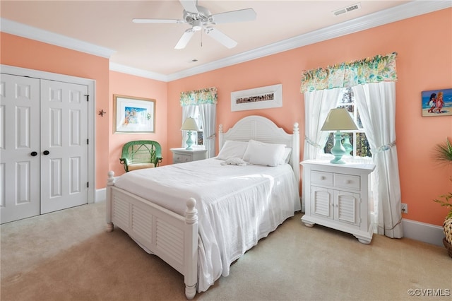 carpeted bedroom featuring ornamental molding, ceiling fan, and a closet