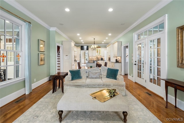 living room with ornamental molding, wood-type flooring, and a chandelier