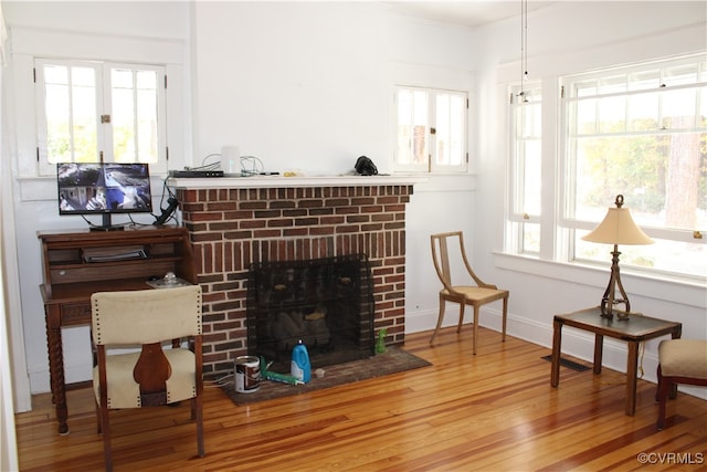 sitting room with a brick fireplace and hardwood / wood-style floors