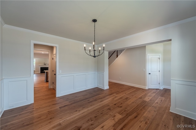 unfurnished dining area featuring wood-type flooring, an inviting chandelier, and crown molding