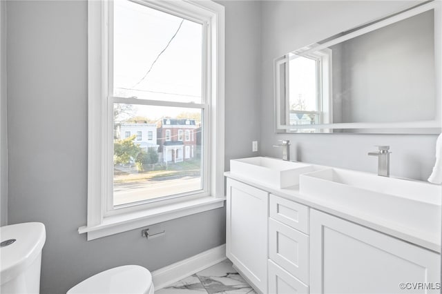 bathroom with plenty of natural light, toilet, and vanity