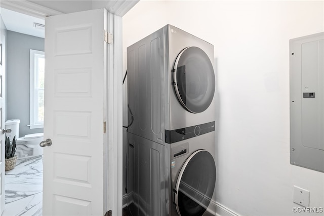 clothes washing area with electric panel and stacked washer and dryer