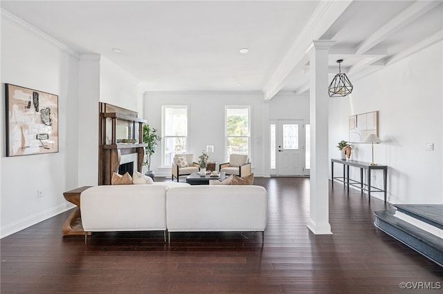 living room featuring dark hardwood / wood-style floors, beam ceiling, ornamental molding, and decorative columns