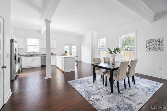 dining room featuring dark hardwood / wood-style floors, a healthy amount of sunlight, beam ceiling, and sink