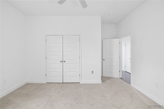 unfurnished bedroom with ceiling fan, light carpet, and a closet