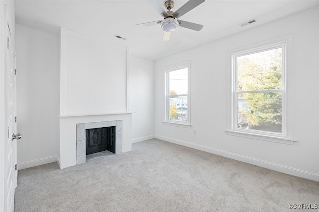 unfurnished living room featuring ceiling fan, light colored carpet, and a tile fireplace