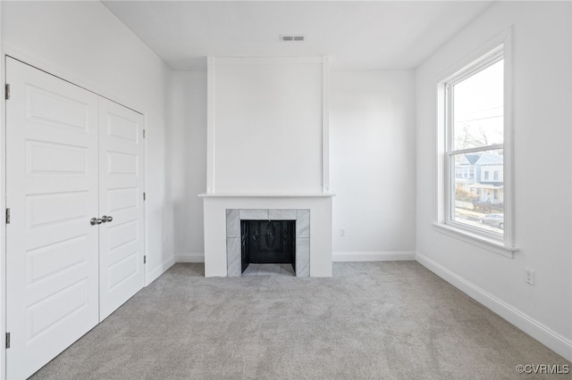 unfurnished living room featuring a tile fireplace and light carpet