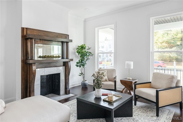 living room with hardwood / wood-style flooring, a healthy amount of sunlight, crown molding, and a tiled fireplace