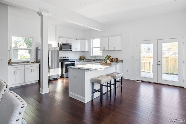 kitchen featuring appliances with stainless steel finishes, dark hardwood / wood-style floors, white cabinetry, and plenty of natural light