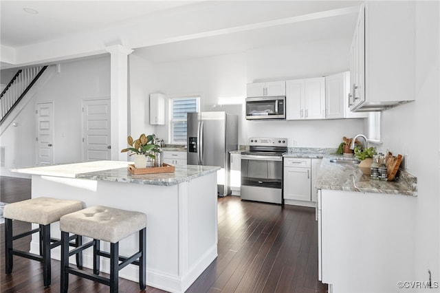 kitchen featuring a breakfast bar, dark wood-type flooring, white cabinets, sink, and appliances with stainless steel finishes