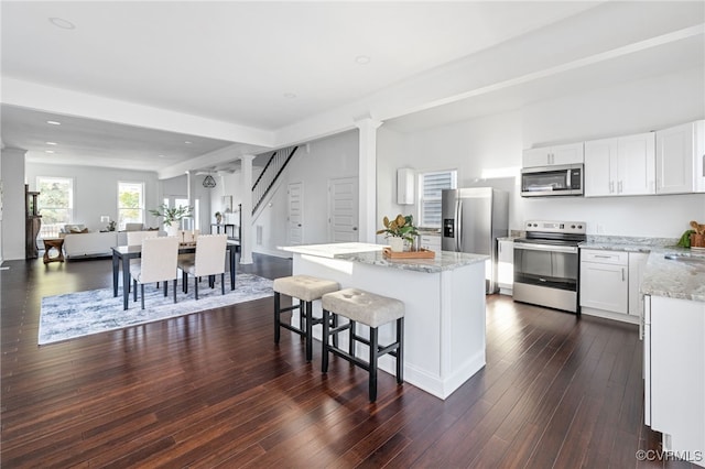 kitchen featuring white cabinets, dark hardwood / wood-style flooring, stainless steel appliances, and light stone countertops