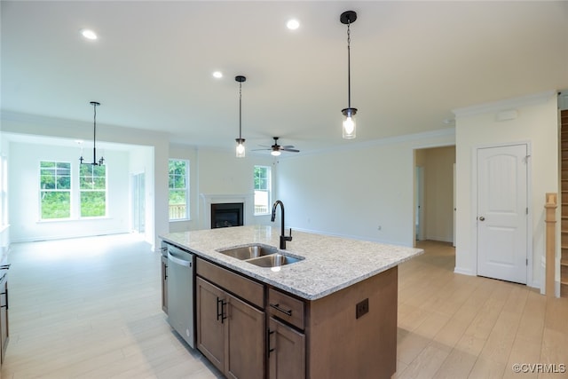 kitchen with an island with sink, hanging light fixtures, sink, and dishwasher