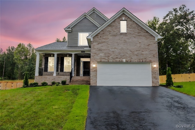 view of front facade featuring a garage, a lawn, and covered porch