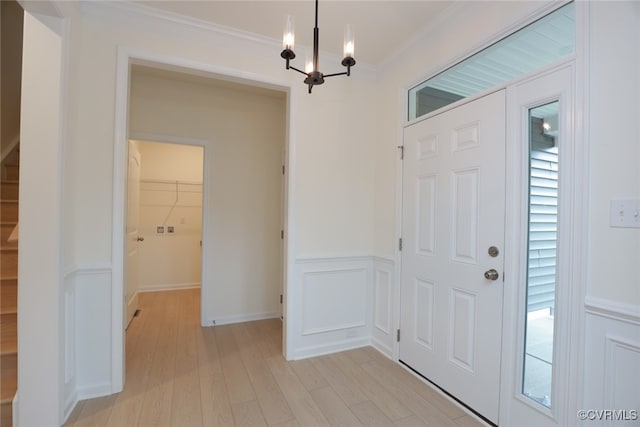 foyer featuring light wood-type flooring, a chandelier, and ornamental molding