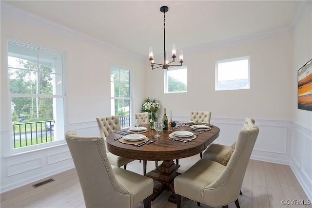 dining space featuring light wood-type flooring, ornamental molding, and plenty of natural light