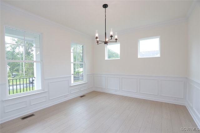 unfurnished room with light wood-type flooring, a notable chandelier, a healthy amount of sunlight, and crown molding