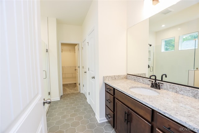 bathroom featuring tile patterned flooring, vanity, and a shower with shower door