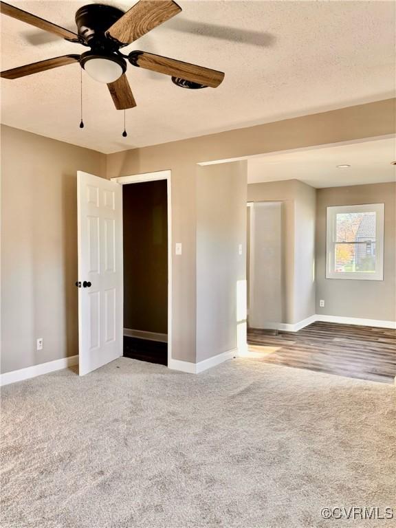 carpeted empty room with ceiling fan and a textured ceiling