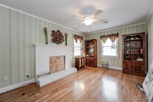 unfurnished room featuring a fireplace, light hardwood / wood-style floors, ceiling fan, and crown molding