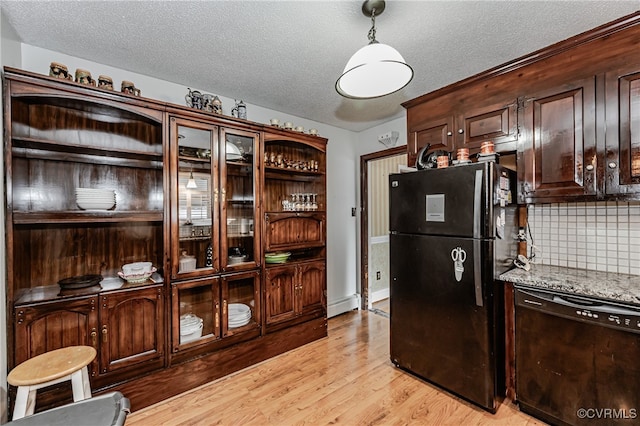 kitchen with dark brown cabinetry, black appliances, light stone counters, backsplash, and light hardwood / wood-style flooring