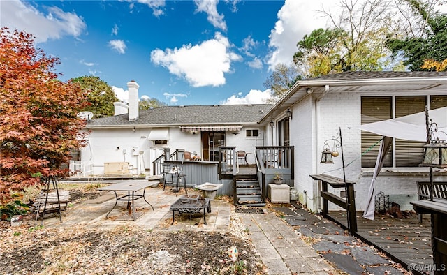 rear view of property with a patio, a wooden deck, and an outdoor fire pit