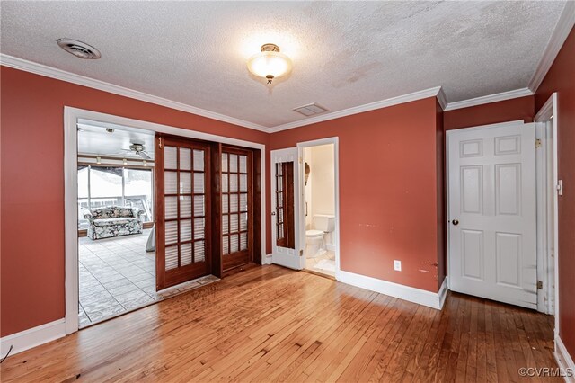 spare room with light wood-type flooring, a textured ceiling, and crown molding