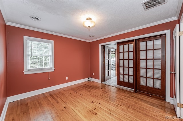 empty room featuring crown molding, a textured ceiling, a healthy amount of sunlight, and light hardwood / wood-style flooring