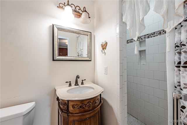 bathroom featuring vanity, toilet, and a tile shower