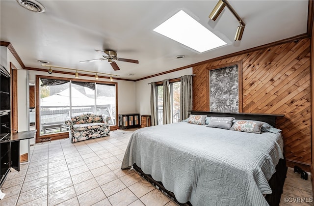 tiled bedroom featuring crown molding, wooden walls, multiple windows, and ceiling fan