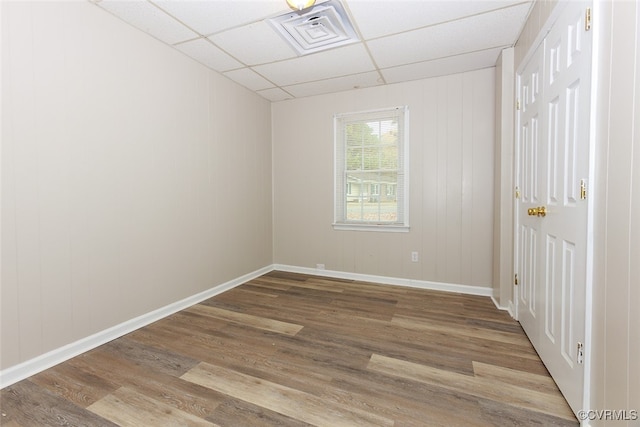 spare room with a drop ceiling and light hardwood / wood-style flooring