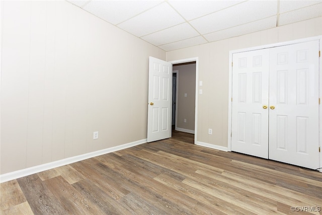 unfurnished bedroom featuring a closet, a drop ceiling, and light hardwood / wood-style flooring