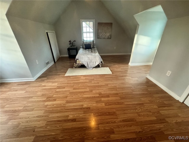 unfurnished bedroom with wood-type flooring and lofted ceiling