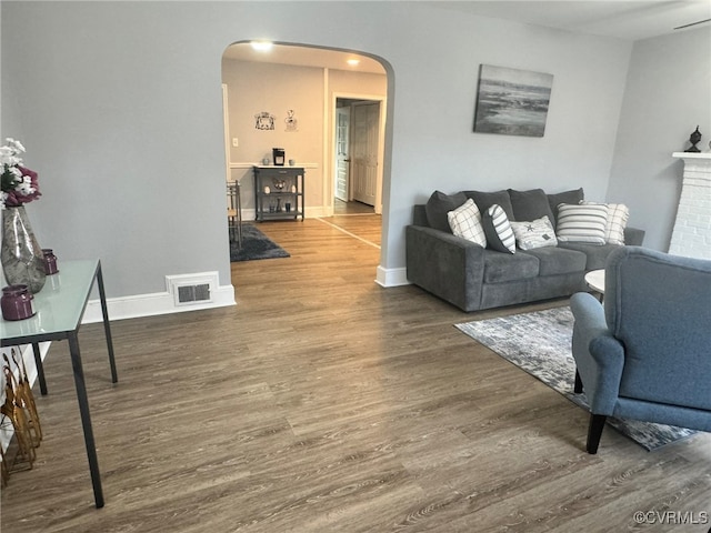 living room with dark wood-type flooring and a fireplace