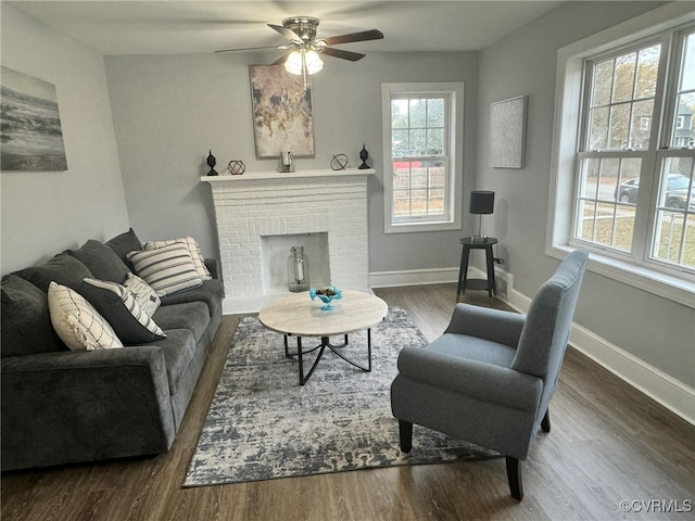 living room featuring hardwood / wood-style flooring, ceiling fan, and a brick fireplace