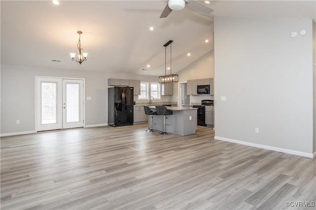 kitchen featuring black appliances, plenty of natural light, a kitchen island, and gray cabinetry