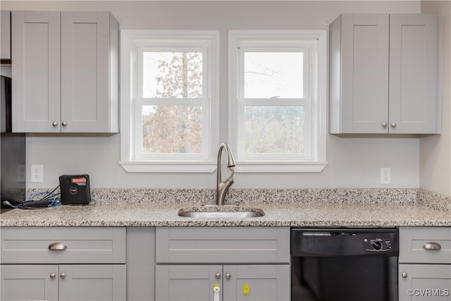 kitchen with light stone counters, sink, and black dishwasher