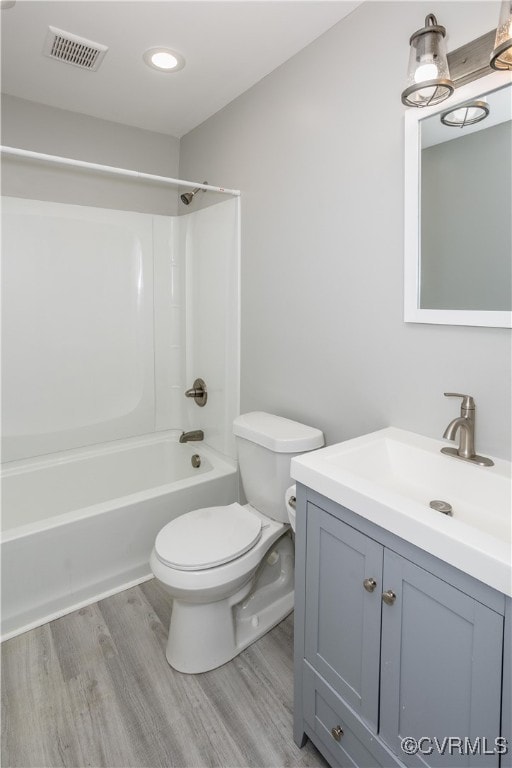 full bathroom featuring washtub / shower combination, hardwood / wood-style floors, vanity, and toilet