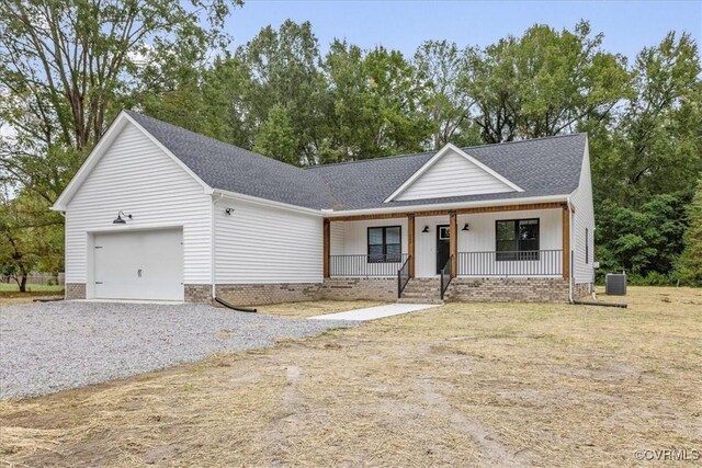 view of front of property with a front lawn, a garage, central air condition unit, and covered porch