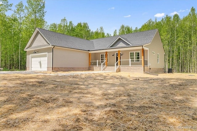 ranch-style house featuring covered porch, roof with shingles, and a garage