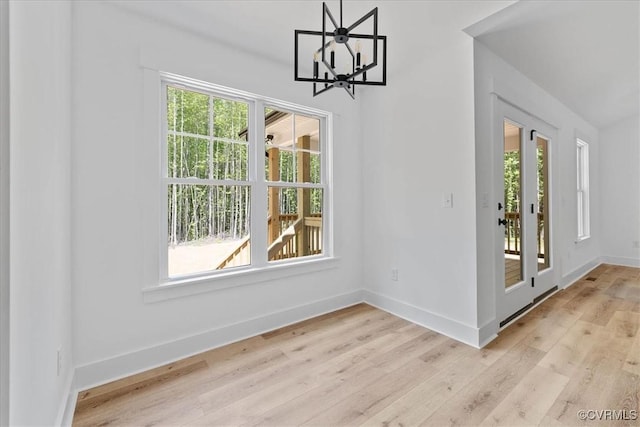 unfurnished dining area featuring light wood finished floors, a chandelier, and baseboards