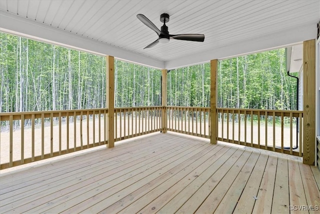wooden deck with a forest view and a ceiling fan