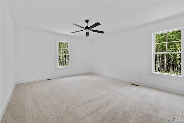 spare room with baseboards, a ceiling fan, visible vents, and carpet