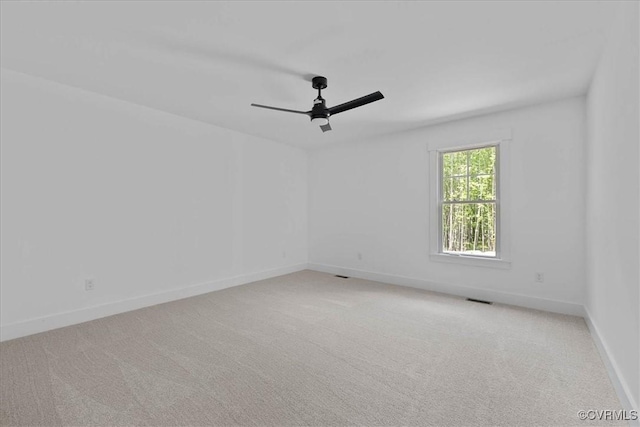 carpeted empty room featuring baseboards, a ceiling fan, and visible vents