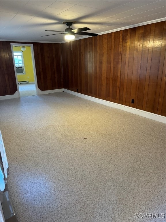 spare room featuring wood walls, ceiling fan, and a baseboard radiator