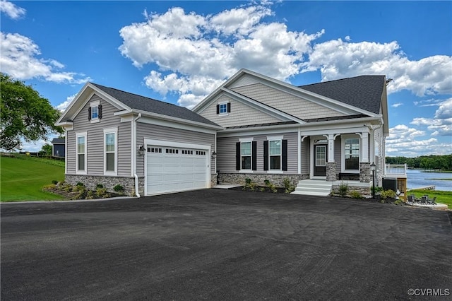 craftsman-style home featuring covered porch, a garage, central air condition unit, and a water view