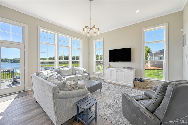 living room with a water view, light wood-type flooring, crown molding, and a wealth of natural light