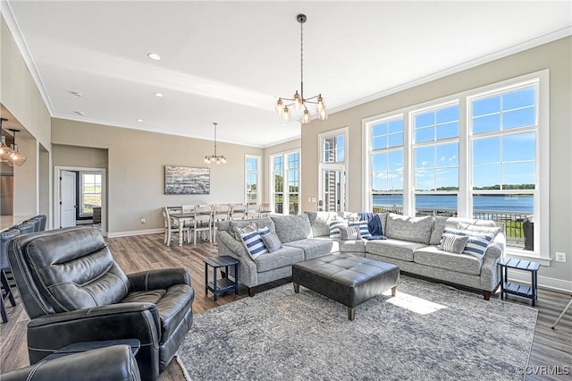 living room featuring plenty of natural light, a water view, wood-type flooring, and a notable chandelier